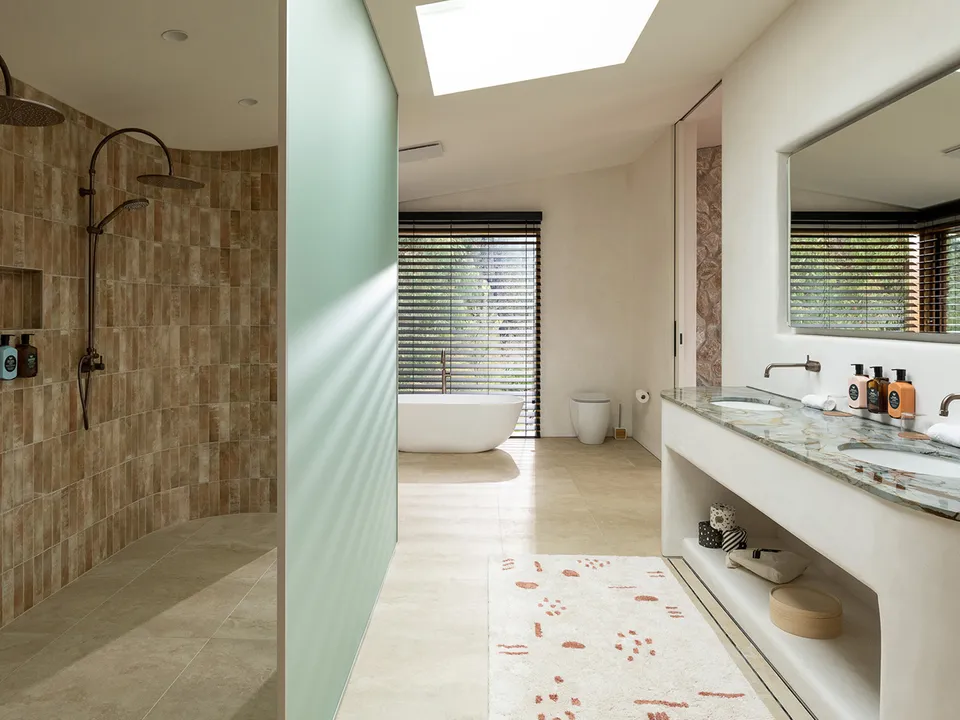 Limestone bathroom with twin rain showers and soaking tub