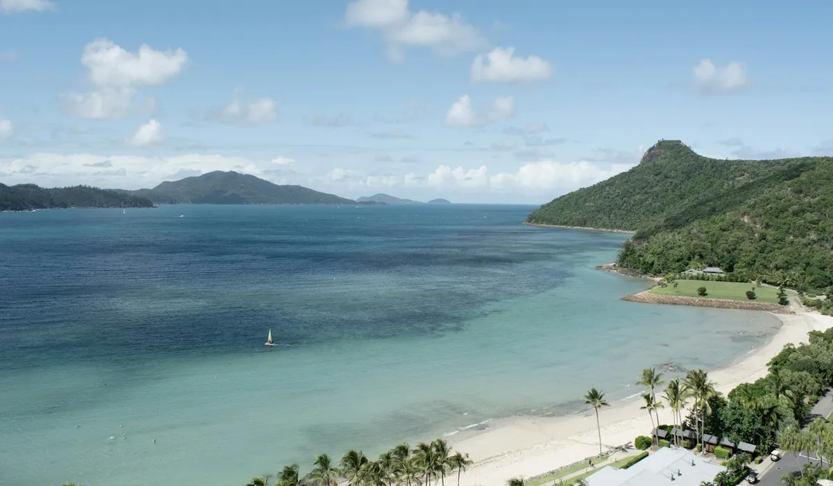 Tropical beach with palm trees and turquoise water at Hamilton Island, Whitsundays