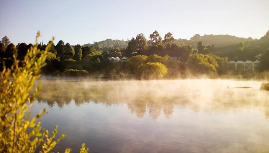 Morning mist rising over Lake Daylesford, with Lake House among the trees