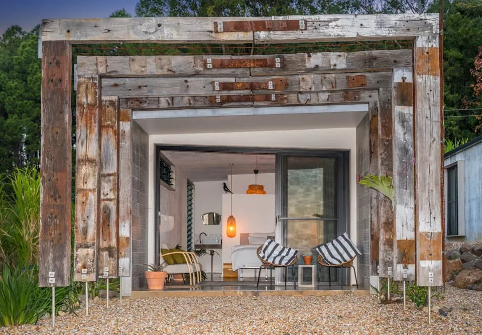 A pavilion framed by reclaimed timber beams at dusk